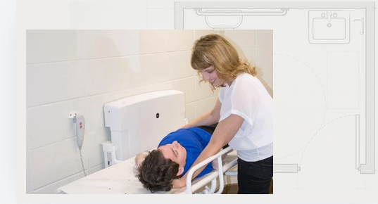 “Mother assisting her son, Greyson, on a powered adult changing table in a Universal Changing Places restroom.”
